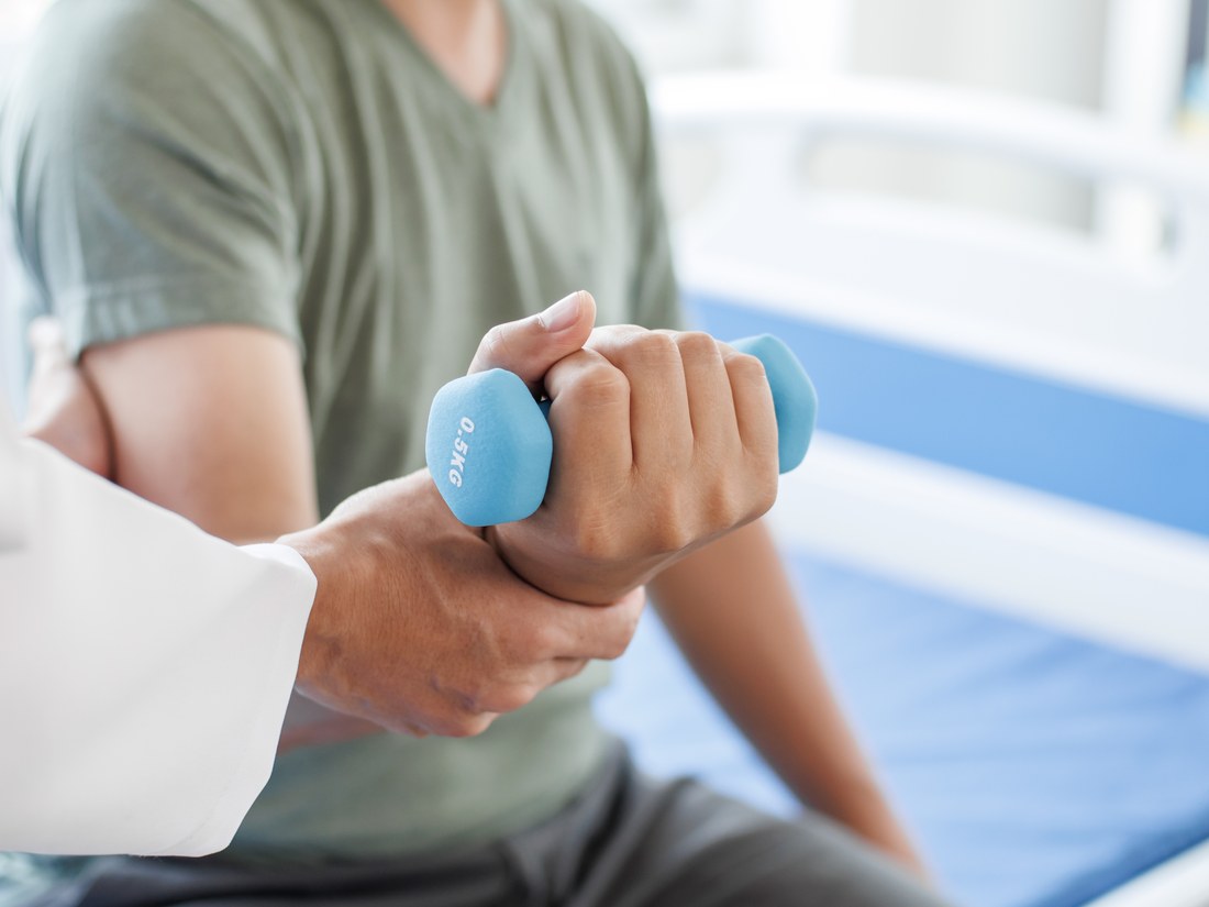 A provider guiding a rehabilitation exercise with a light dumbbell